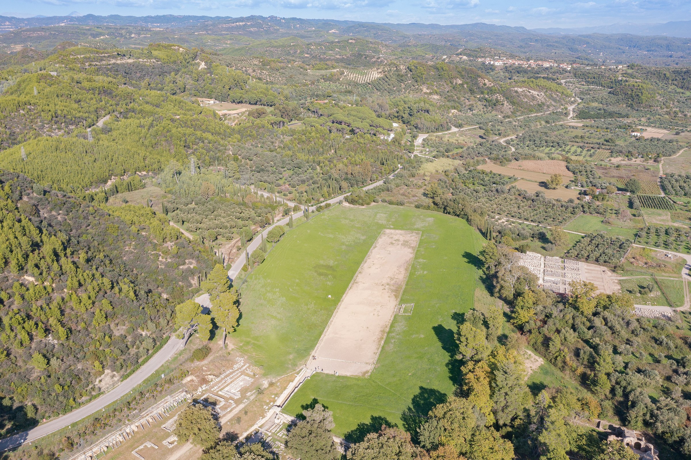 Aerial view of the ancient stadium of Olympia and its surrounding wooded landscape.